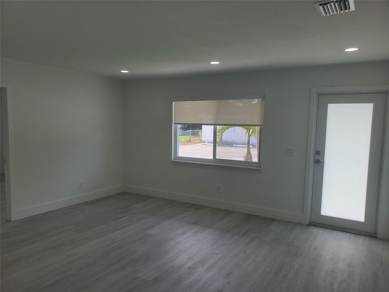 An empty room with white walls, light wood-look flooring, recessed lighting, and a glass-paneled door — 70 NW 13th Avenue # 2, Dania Beach FL 33004, DANIA BEACH, FL