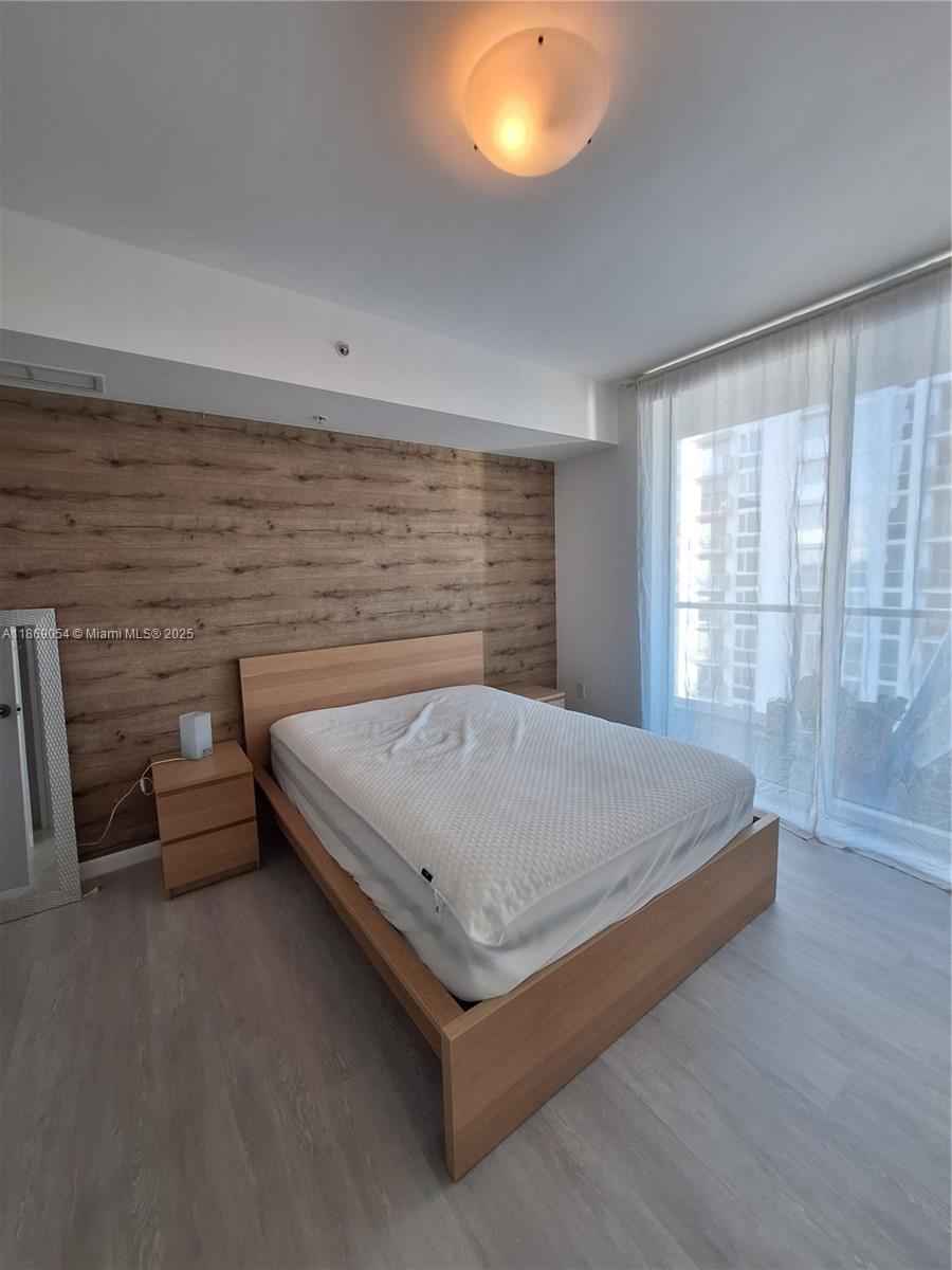 A bedroom features a wood-paneled accent wall, a platform bed, and floor-to-ceiling windows — 253 NE 2nd St # 2606, Miami FL 33132, MIAMI, FL