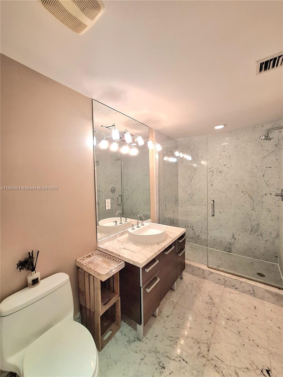 A bathroom features a vessel sink vanity, a glass-enclosed shower, and marble-style tile flooring — 253 NE 2nd St # 2606, Miami FL 33132, MIAMI, FL