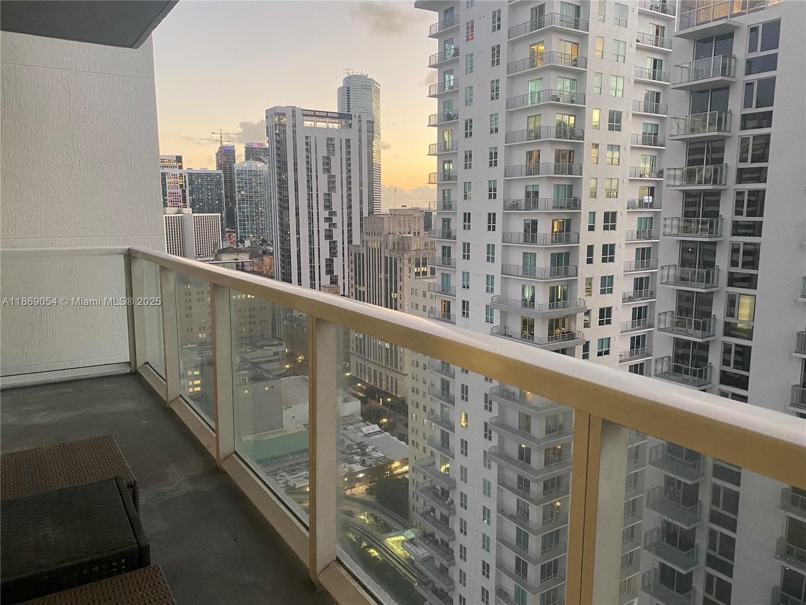 A high-rise balcony overlooks a dense urban cityscape with multiple residential towers at sunset — 253 NE 2nd St # 2606, Miami FL 33132, MIAMI, FL