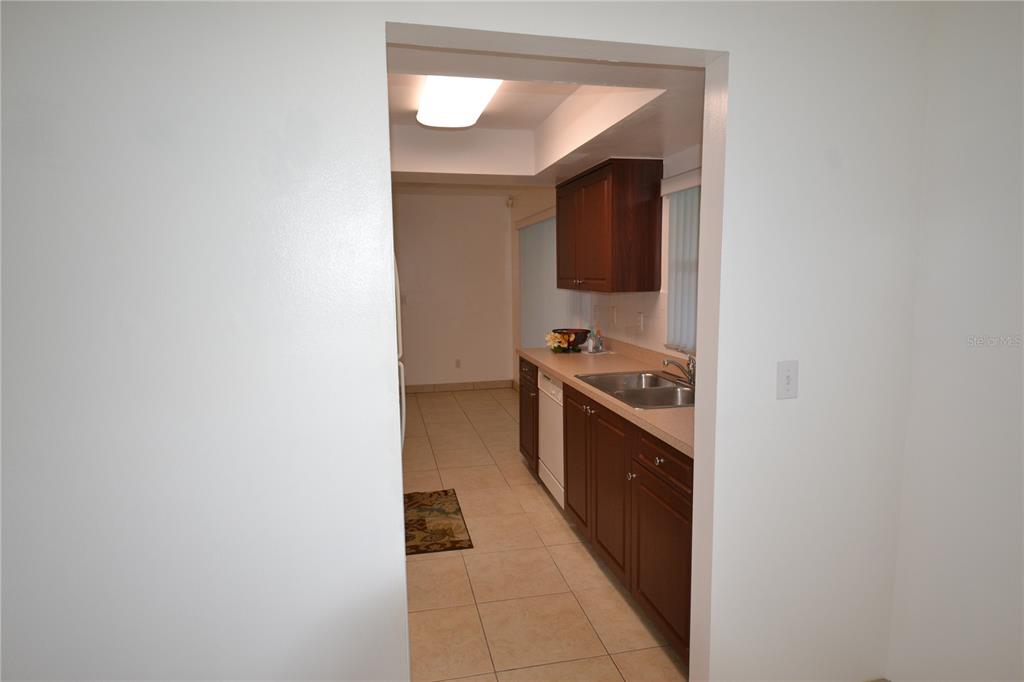 A view through a doorway into a kitchen with dark wood cabinets and tile flooring — 2357 WHITE OAK CIRCLE, CLEARWATER, FL