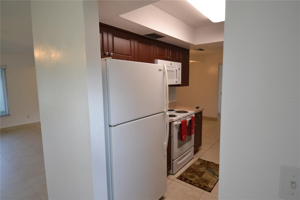 A kitchen features white appliances, dark wood cabinets, and light tile flooring — 2357 WHITE OAK CIRCLE, CLEARWATER, FL