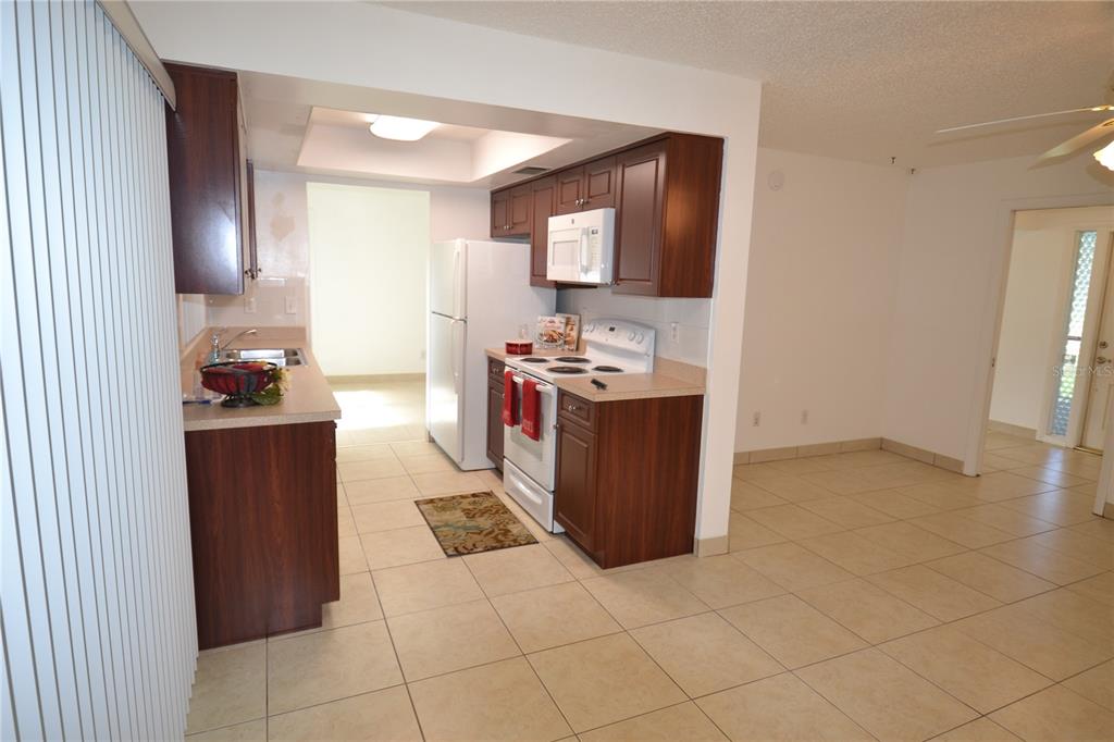 A kitchen features dark wood cabinets, white appliances, and beige tile flooring — 2357 WHITE OAK CIRCLE, CLEARWATER, FL