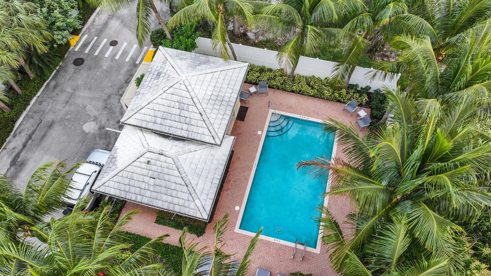 An aerial view shows a swimming pool with a brick deck and a nearby building — 109 E Coda Circle, Delray Beach FL 33444, DELRAY BEACH, FL