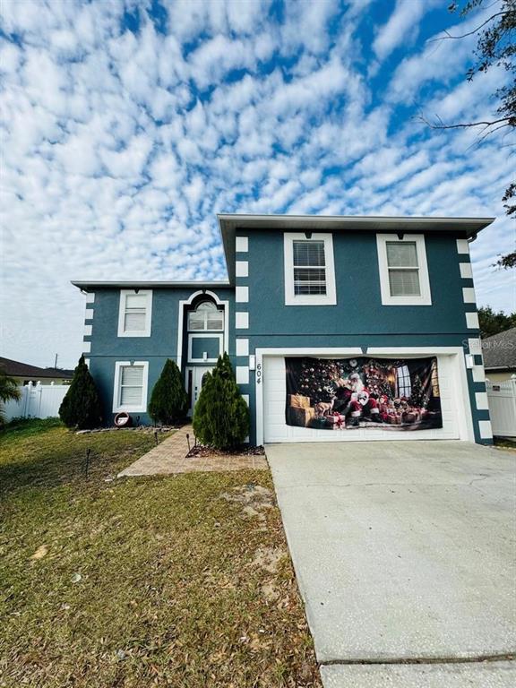A two-story blue house with white trim and a garage door decorated with Santa Claus — 604 TAMARIN LANE, KISSIMMEE, FL