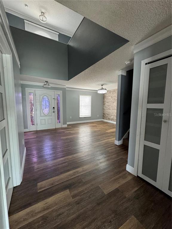 An entryway with wood-look flooring leads to a front door and an open living area — 604 TAMARIN LANE, KISSIMMEE, FL