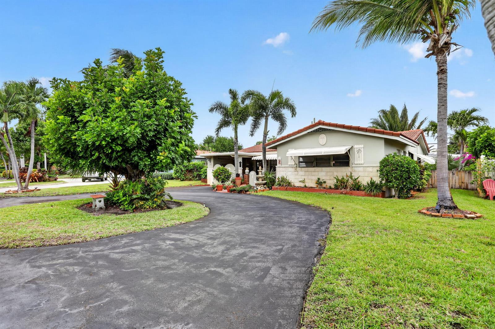 A single-story house with a curved driveway, palm trees, and a large green tree — 1931 NE 27th Street, Lighthouse Point FL 33064, LIGHTHOUSE POINT, FL