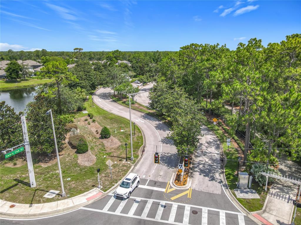 An aerial view shows a gated entrance with a crosswalk, traffic lights, and surrounding trees — 600 GARDEN CLUB DRIVE, DELAND, FL