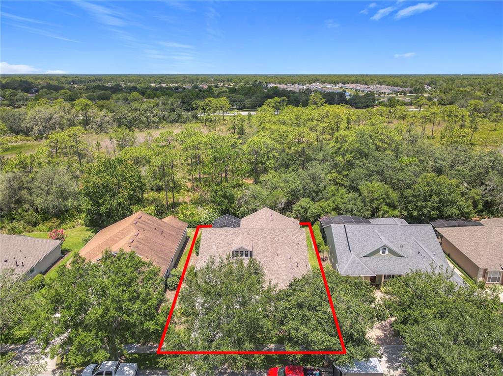 An aerial view shows a residential house outlined in red surrounded by trees and neighboring homes — 600 GARDEN CLUB DRIVE, DELAND, FL