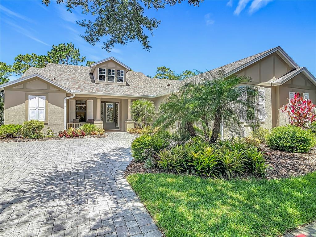 A tan single-story house with a paved driveway, a front porch, and lush landscaping — 600 GARDEN CLUB DRIVE, DELAND, FL