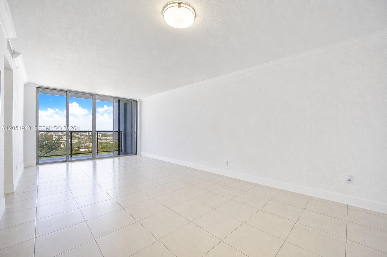 An empty room with white walls, light tile flooring, and a sliding glass balcony door — 401 69th St # 1411, Miami Beach FL 33141, MIAMI BEACH, FL