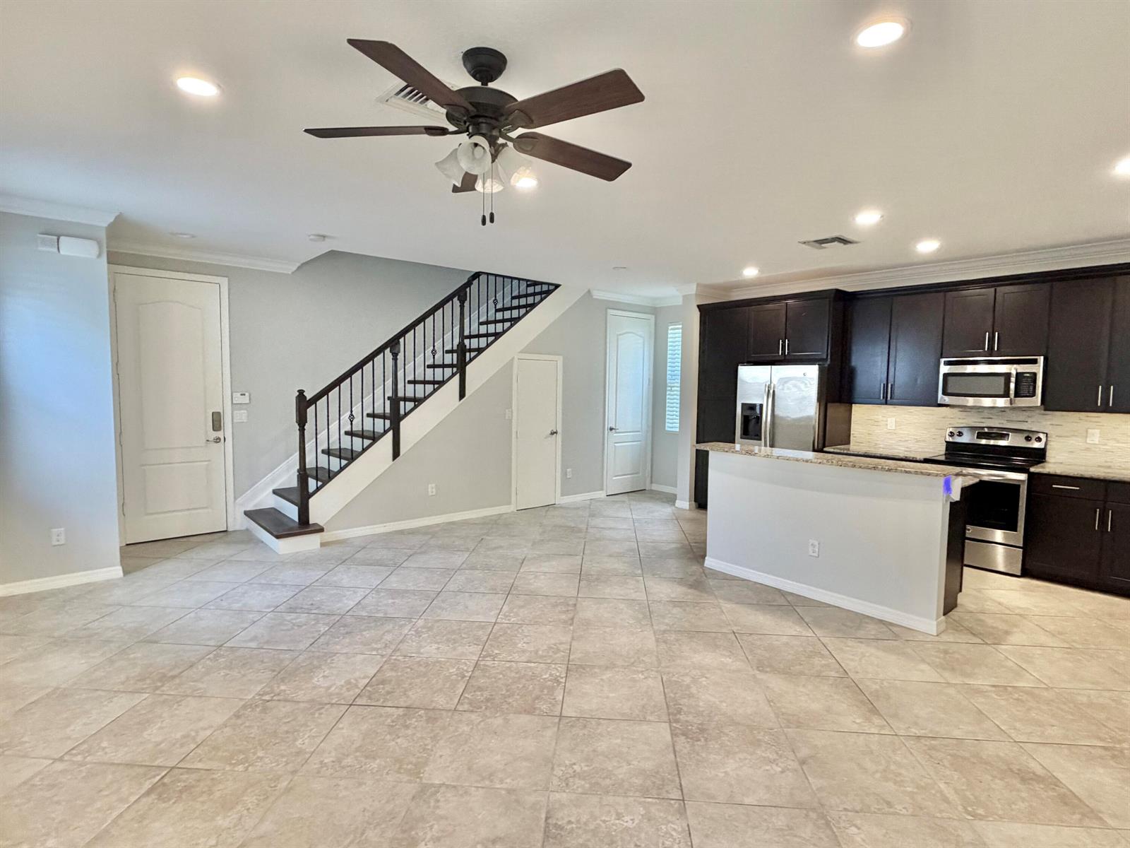 An open-concept kitchen and living area features tile flooring, dark cabinetry, and a staircase — 123 N K Street # B, FL 33460, FL