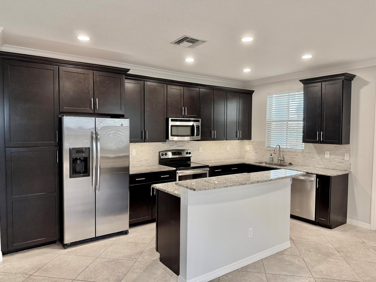A kitchen features dark wood cabinets, stainless steel appliances, granite countertops, and a central island — 123 N K Street # B, FL 33460, FL