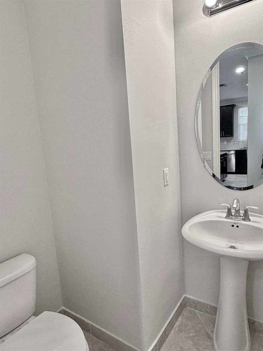 A half bathroom features a pedestal sink, an oval mirror, and a toilet — 123 N K Street # B, FL 33460, FL