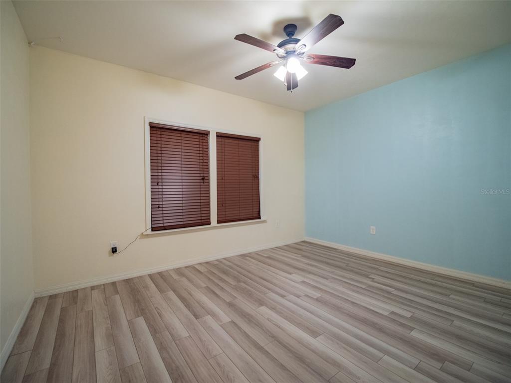 An empty bedroom features light-colored walls, a blue accent wall, and wood-look laminate flooring — 19346 NW 228TH STREET, HIGH SPRINGS, FL