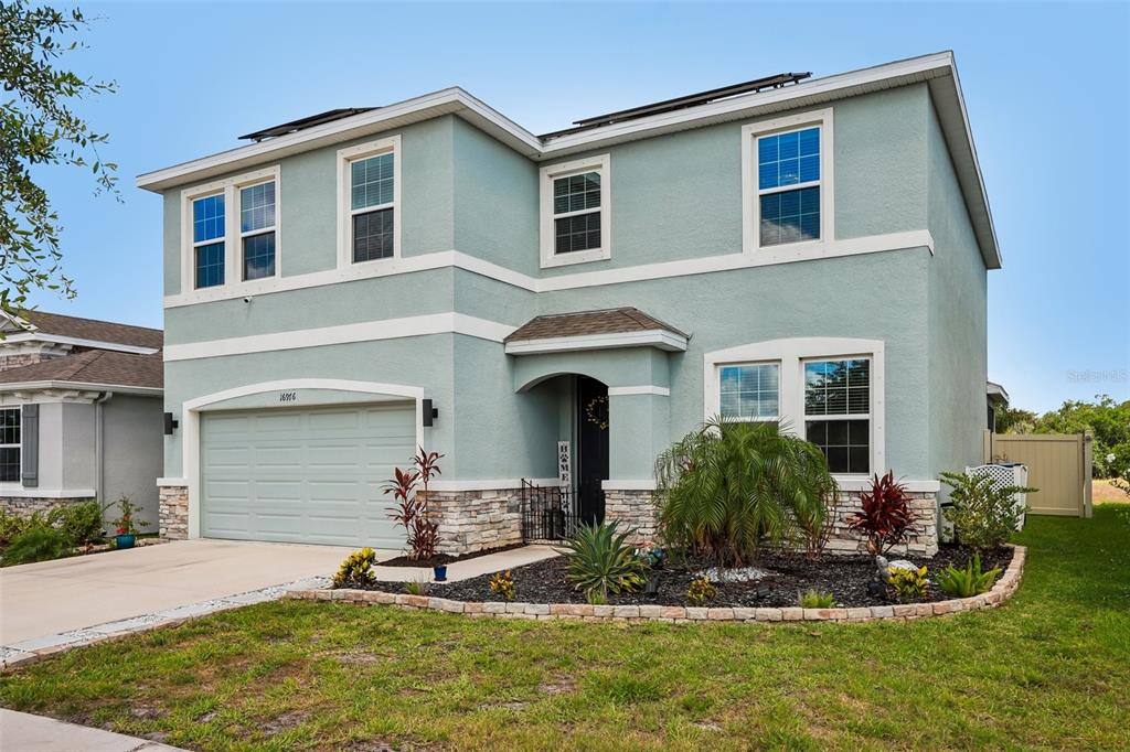 A two-story house with light blue stucco siding, a stone veneer base, and a garage — 16976 OVAL RUM DRIVE, WIMAUMA, FL