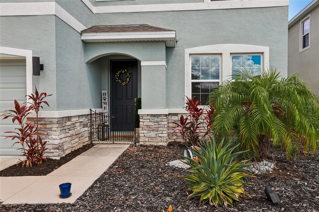 The exterior of a house features a dark front door, stone siding, and landscaping — 16976 OVAL RUM DRIVE, WIMAUMA, FL