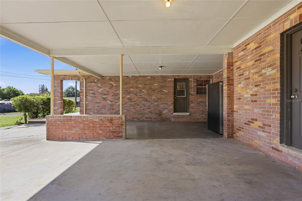 A covered brick carport features a concrete floor, two support posts, and two exterior doors — 620 W CUMMINGS STREET, LAKE ALFRED, FL