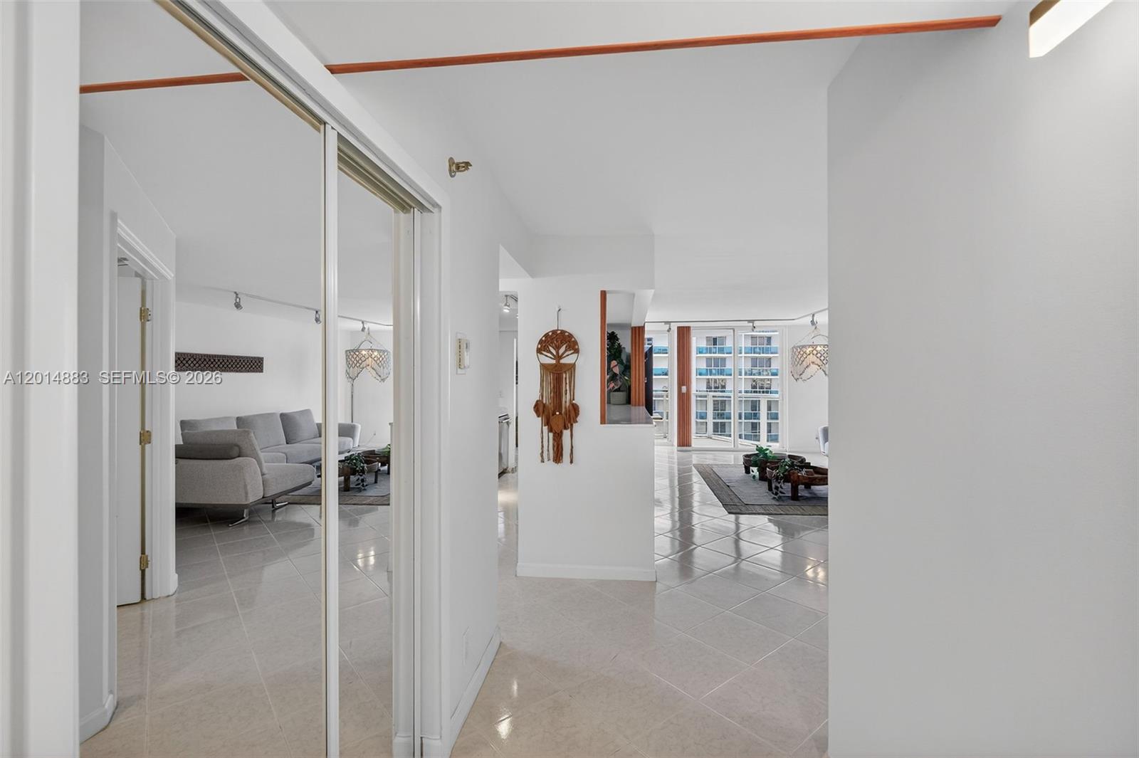 A hallway with mirrored closet doors leads to an open-concept living area with tiled floors — 2401 Collins Ave # 1406, Miami Beach FL 33140, MIAMI BEACH, FL