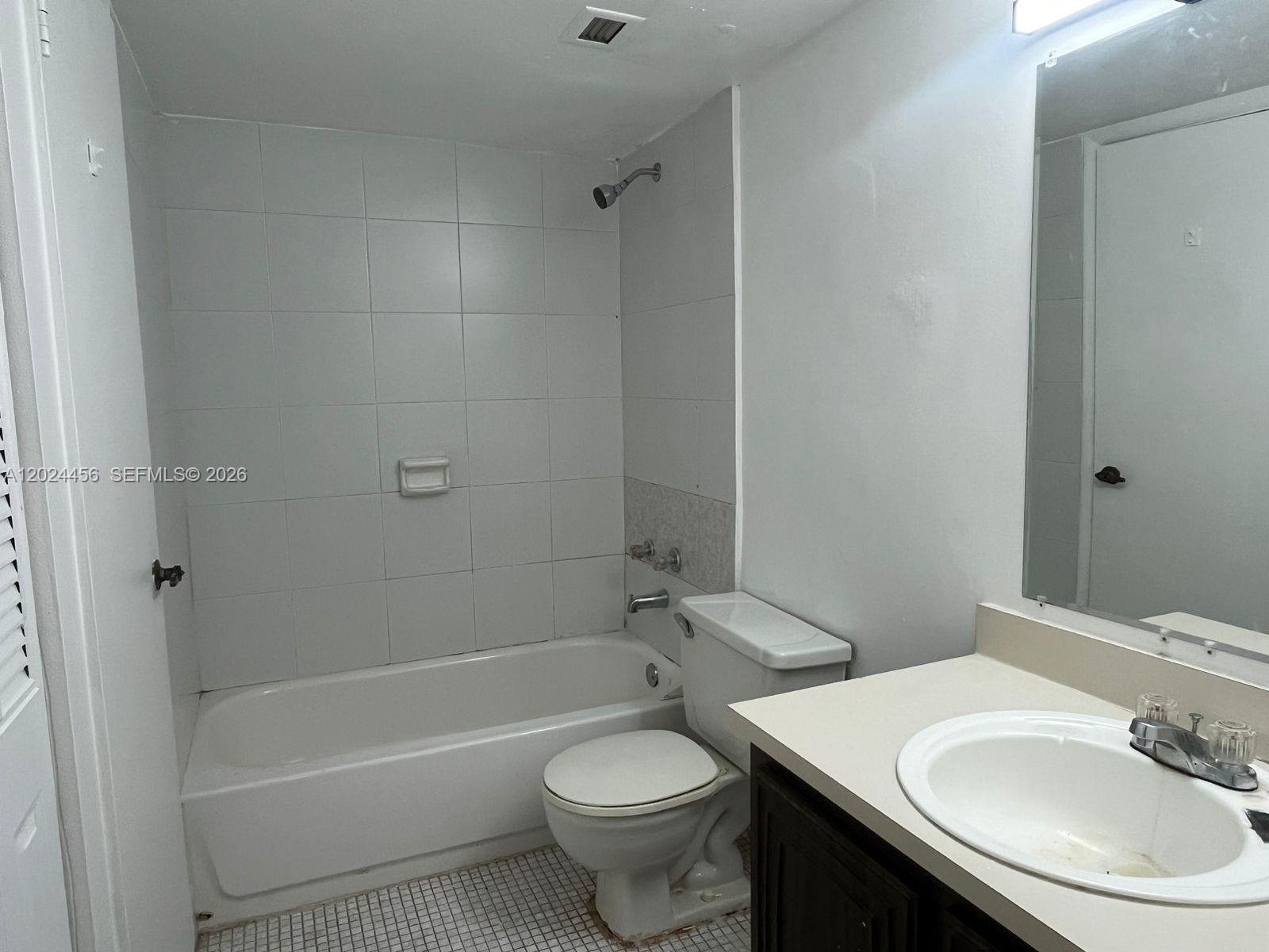 A bathroom vanity features a beige countertop, a white sink, and dark wood cabinets — 484 NW 165th St Rd # 111, Miami FL 33169, MIAMI, FL