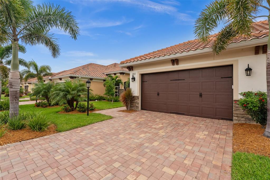 A single-story house with a brown garage door, tiled roof, and a paved driveway — 121 COLEBROOK COURT, VENICE, FL