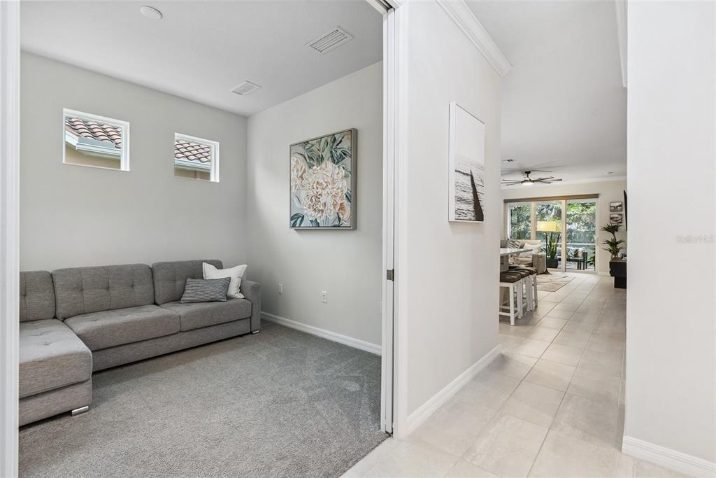 A carpeted room with a gray sectional sofa connects to a tiled living area — 121 COLEBROOK COURT, VENICE, FL