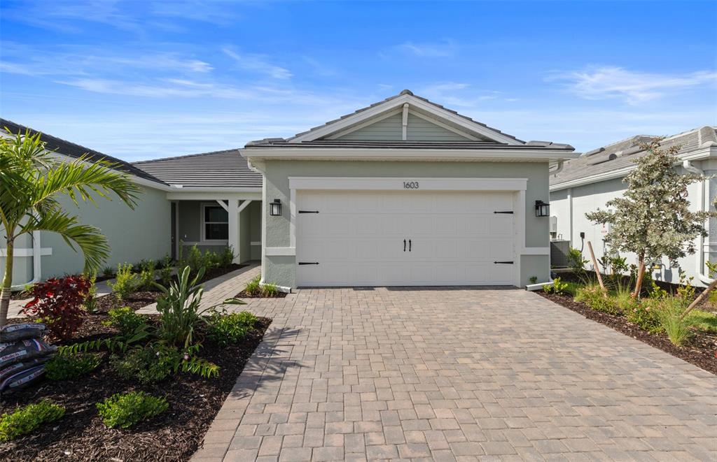 A single-story house with a paved driveway, a two-car garage, and light green siding — 1603 TAVIRA PLACE, ENGLEWOOD, FL
