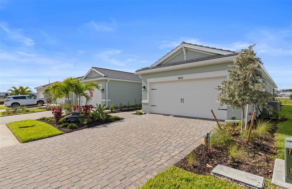A view of two suburban houses with paved driveways and landscaped front yards — 1603 TAVIRA PLACE, ENGLEWOOD, FL
