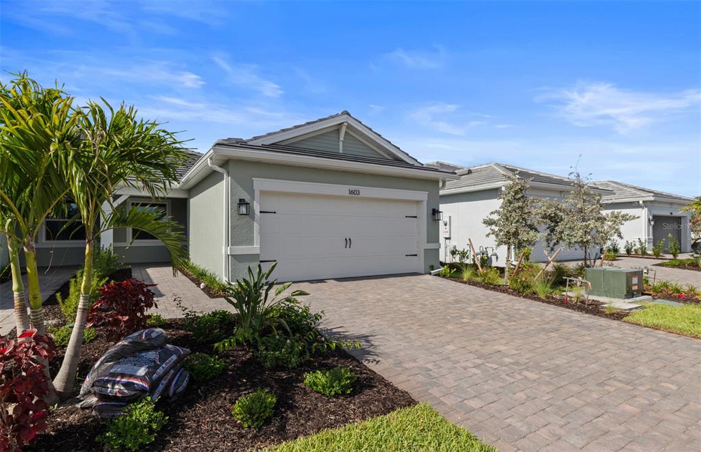 A single-story house with a light green exterior, a two-car garage, and a paved driveway — 1603 TAVIRA PLACE, ENGLEWOOD, FL