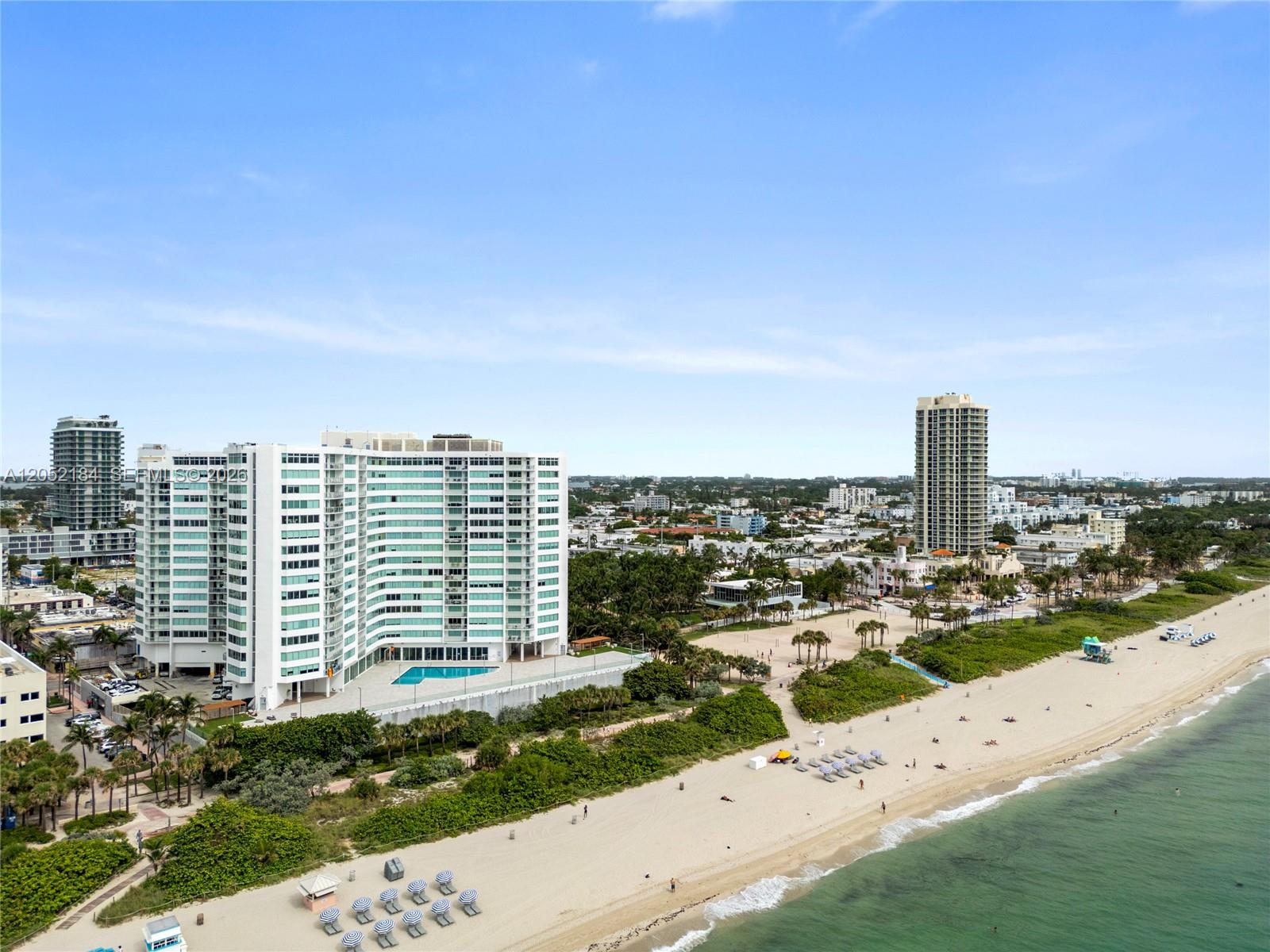 An aerial view shows a large white apartment building beside a sandy beach and ocean — 7135 Collins Ave # 1535, Miami Beach FL 33141, MIAMI BEACH, FL