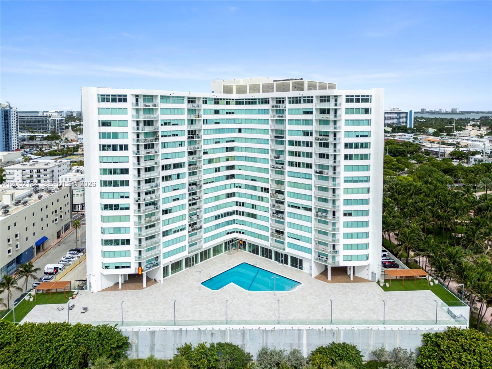An aerial view shows a tall white residential building with a V-shaped swimming pool — 7135 Collins Ave # 1535, Miami Beach FL 33141, MIAMI BEACH, FL