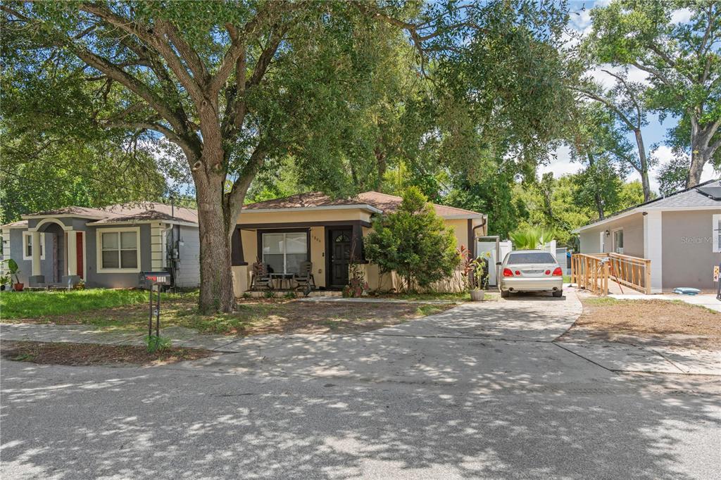 A single-story house with a front porch, a driveway, and a large tree in front — 1806 E CURTIS STREET, TAMPA, FL