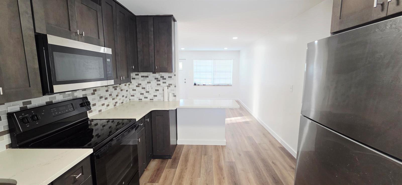 A kitchen features dark wood cabinets, stainless steel appliances, and a white quartz peninsula — 765 W 7th Street # B, Riviera Beach FL 33404, RIVIERA BEACH, FL