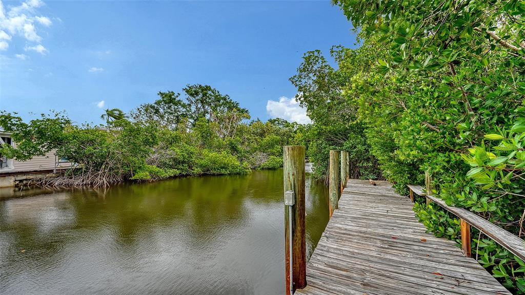 A wooden dock extends into a narrow canal surrounded by dense green mangrove trees — 4324 SALTWATER PEARL WAY, CORTEZ, FL