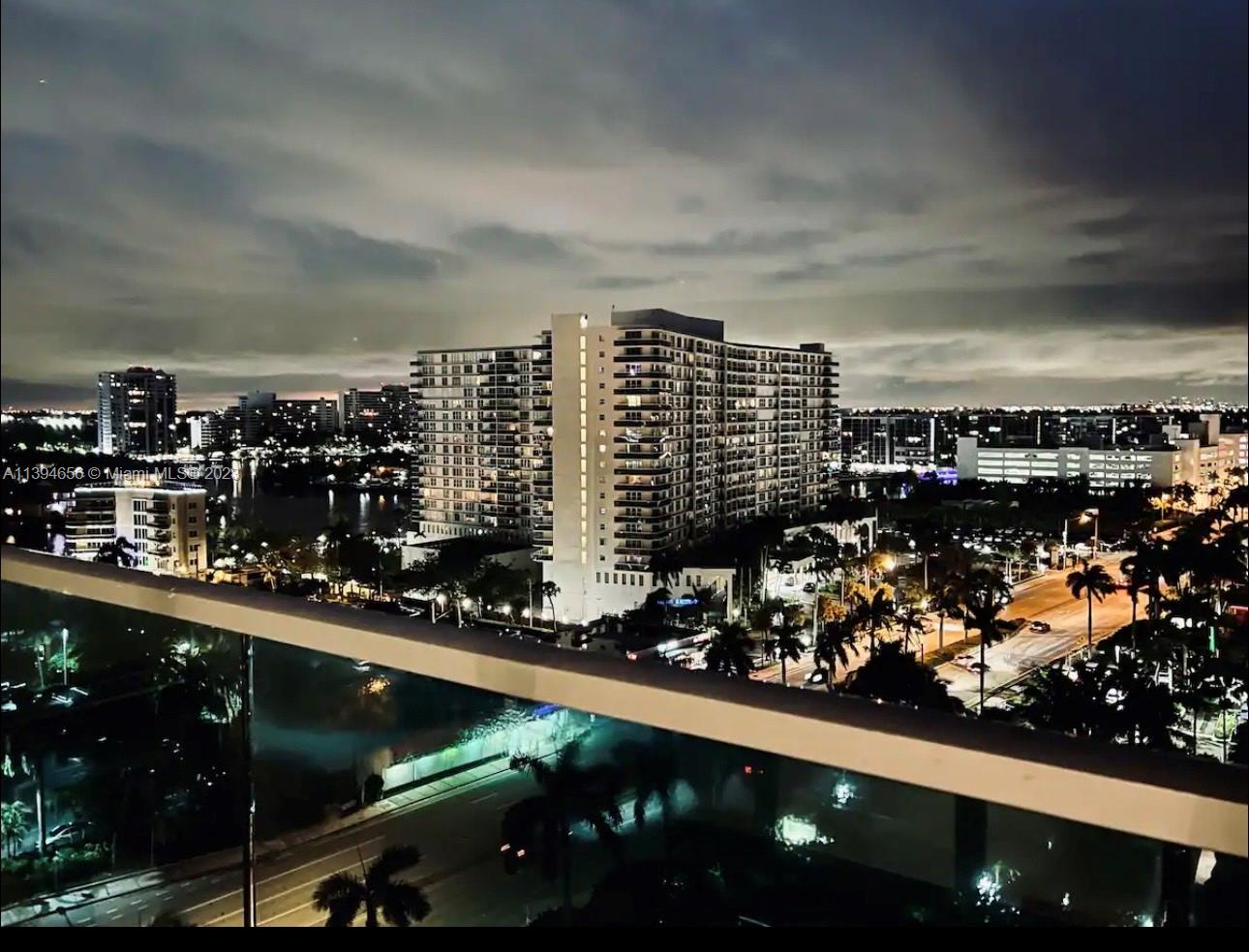 A night view from a balcony overlooking city buildings, a road, and palm trees — 4001 S Ocean Dr # 14H, Hollywood FL 33019, HOLLYWOOD, FL