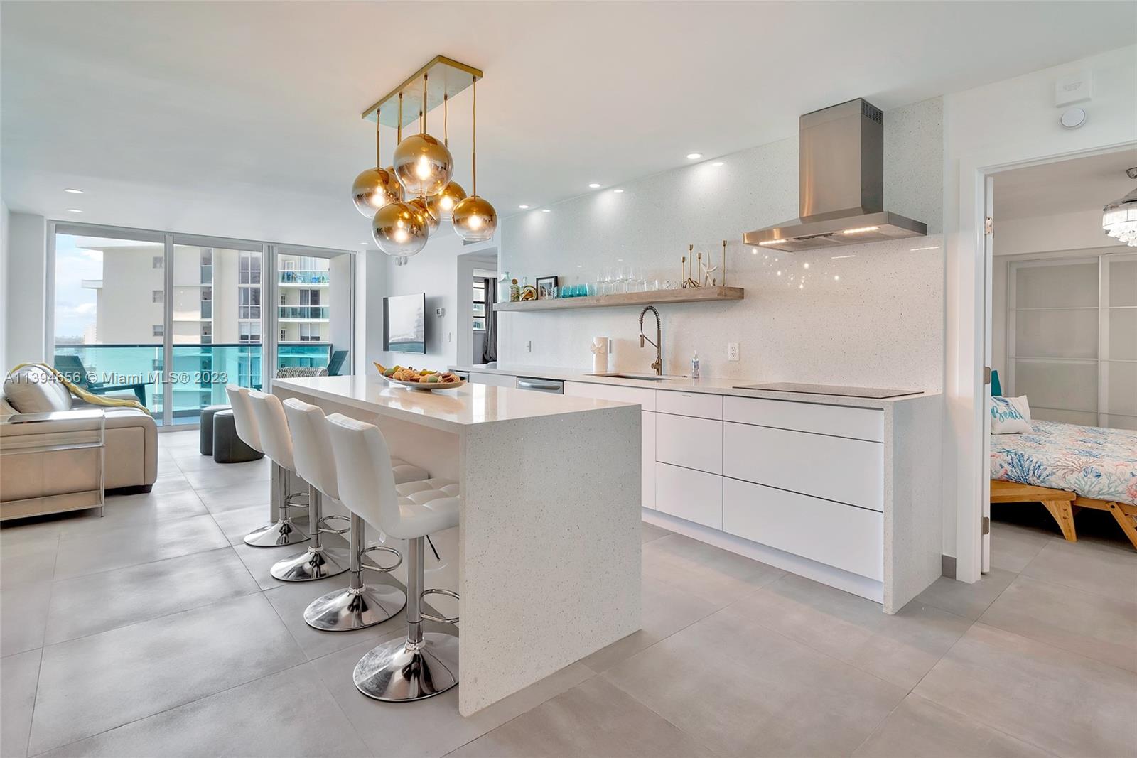 A modern kitchen features a white quartz island, bar stools, and a stainless steel range hood — 4001 S Ocean Dr # 14H, Hollywood FL 33019, HOLLYWOOD, FL