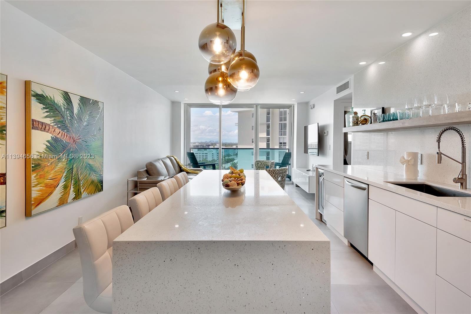 A modern kitchen features a long white quartz island, pendant lighting, and a balcony view — 4001 S Ocean Dr # 14H, Hollywood FL 33019, HOLLYWOOD, FL