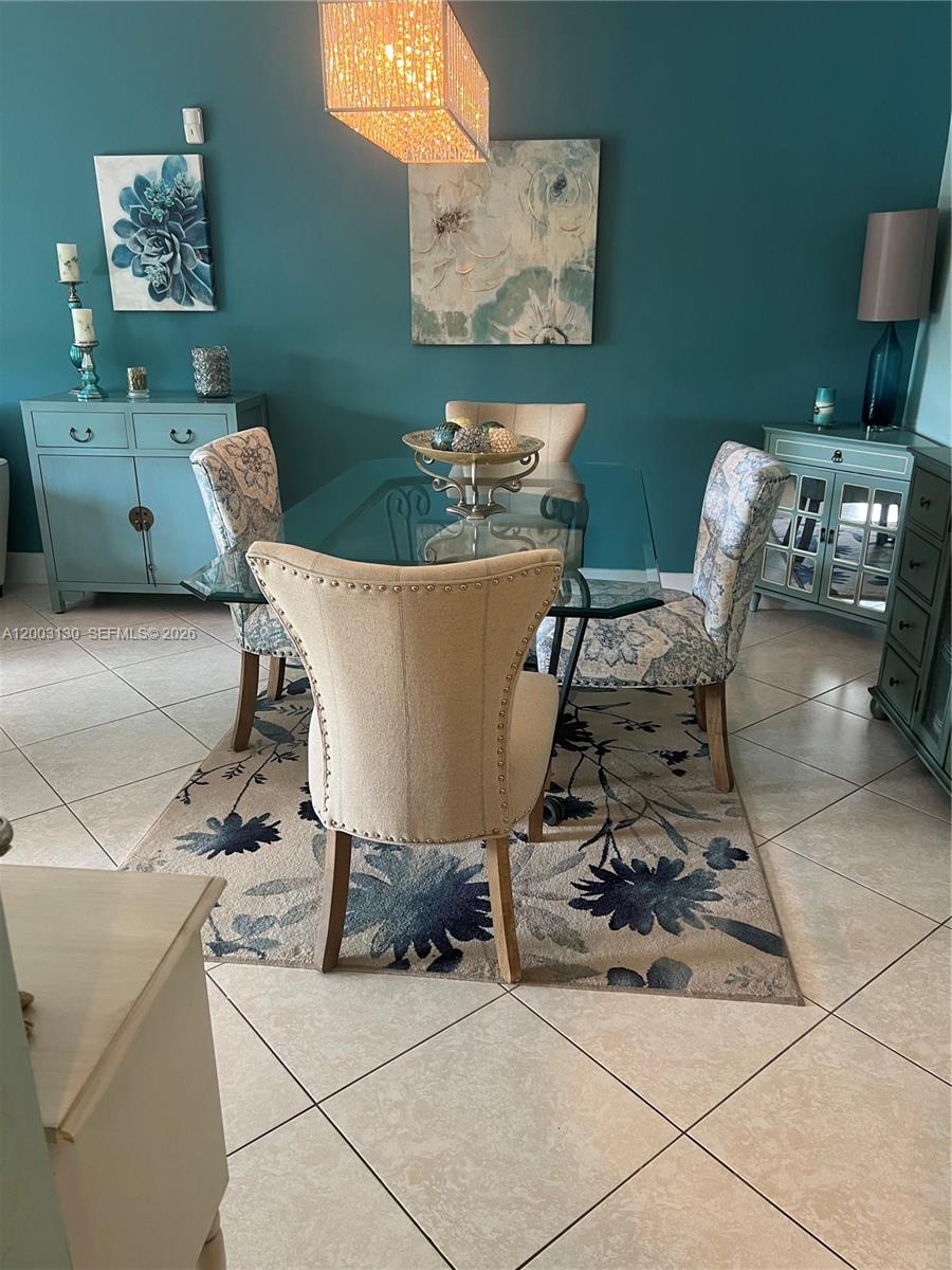 A dining room features a glass-topped table, upholstered chairs, and teal cabinets on a tiled floor — 8335 SW 72nd Ave # 212D, Miami FL 33143, MIAMI, FL