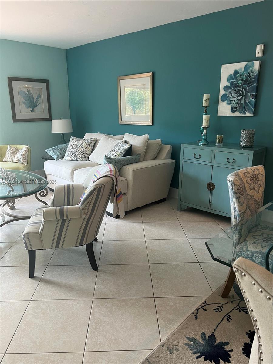 A living room features a light-colored sofa, patterned armchairs, and a teal accent wall — 8335 SW 72nd Ave # 212D, Miami FL 33143, MIAMI, FL