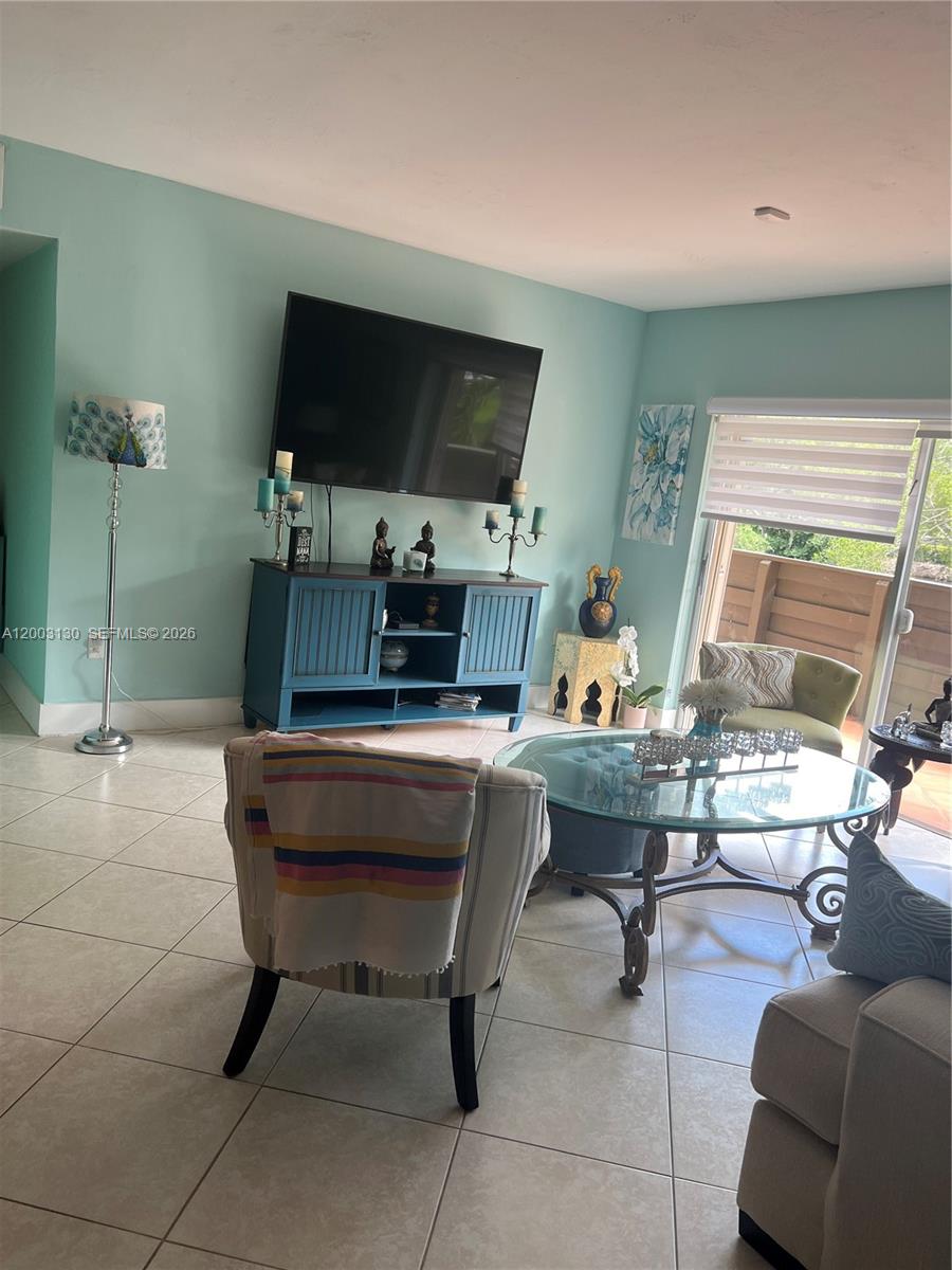A living room features light blue walls, tile flooring, a television, and a glass coffee table — 8335 SW 72nd Ave # 212D, Miami FL 33143, MIAMI, FL
