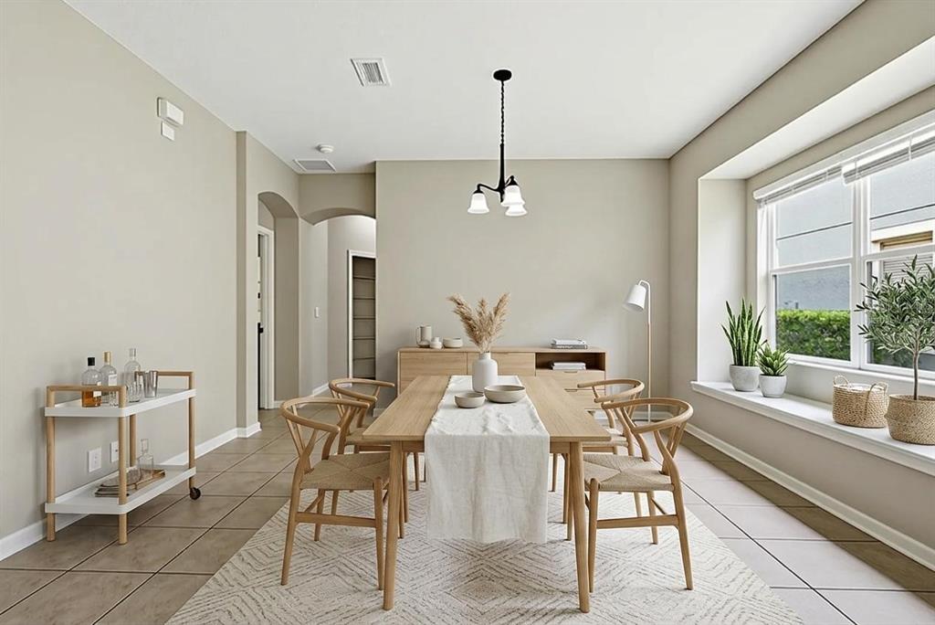 A dining room features a wooden table, woven chairs, a bar cart, and a window seat — 207 MANOR VIEW LANE, DELAND, FL
