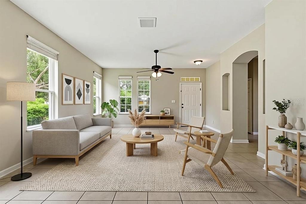 A living room features a grey sofa, two wooden chairs, a coffee table, and tile flooring — 207 MANOR VIEW LANE, DELAND, FL