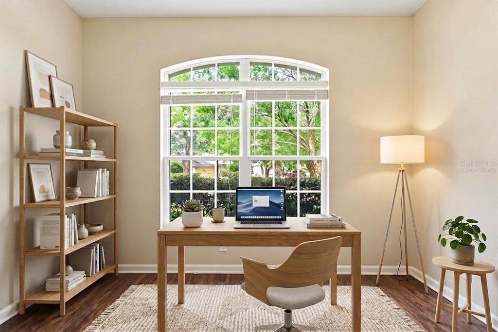 This is a virtually staged home office featuring a desk, chair, bookshelf, and large window — 207 MANOR VIEW LANE, DELAND, FL