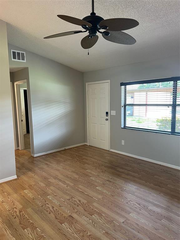 A living room features hardwood floors, a ceiling fan, a white door, and a window — 12449 ORANGEWOOD CIRCLE UNIT 17, TAVARES, FL