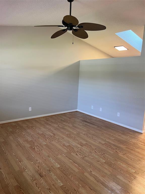 An empty room features light wood flooring, gray walls, a ceiling fan, and a skylight — 12449 ORANGEWOOD CIRCLE UNIT 17, TAVARES, FL