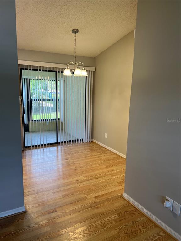 A dining area features hardwood floors, a chandelier, and sliding glass doors to a patio — 12449 ORANGEWOOD CIRCLE UNIT 17, TAVARES, FL