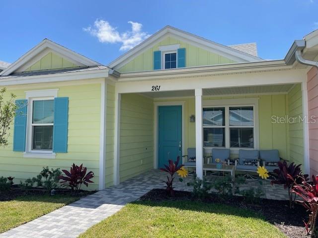 A light yellow house with a teal front door and blue shutters features a porch — 261 GYPSY PALACE LANE, DAYTONA BEACH, FL