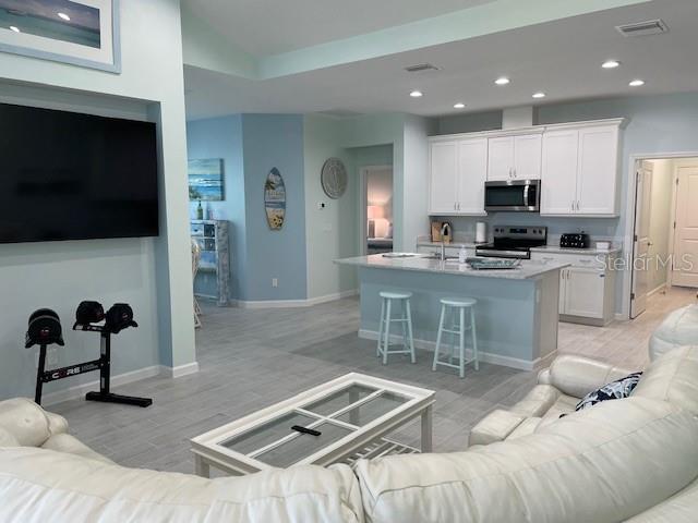 A living room with a large television, white sofa, and an open kitchen with island seating — 261 GYPSY PALACE LANE, DAYTONA BEACH, FL