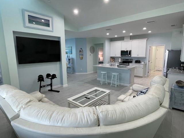 A living room with a large white sectional sofa faces a wall-mounted television and kitchen — 261 GYPSY PALACE LANE, DAYTONA BEACH, FL