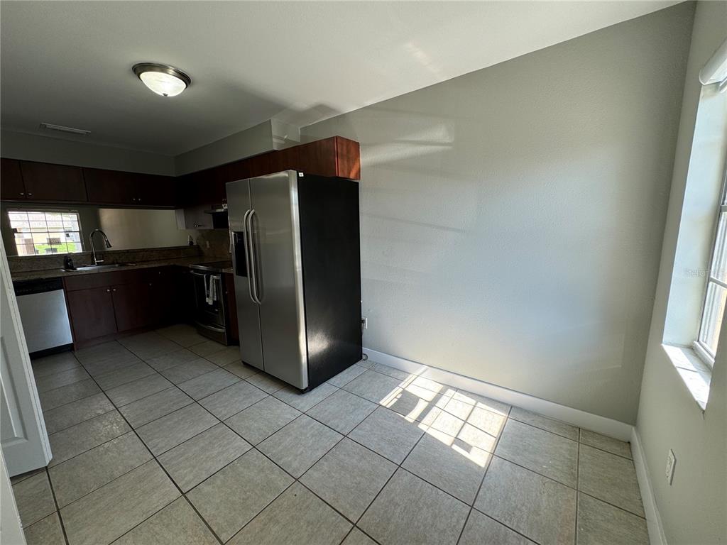 A kitchen features dark wood cabinets, stainless steel appliances, and light-colored tile flooring — 1357 SOPHIE BOULEVARD, ORLANDO, FL